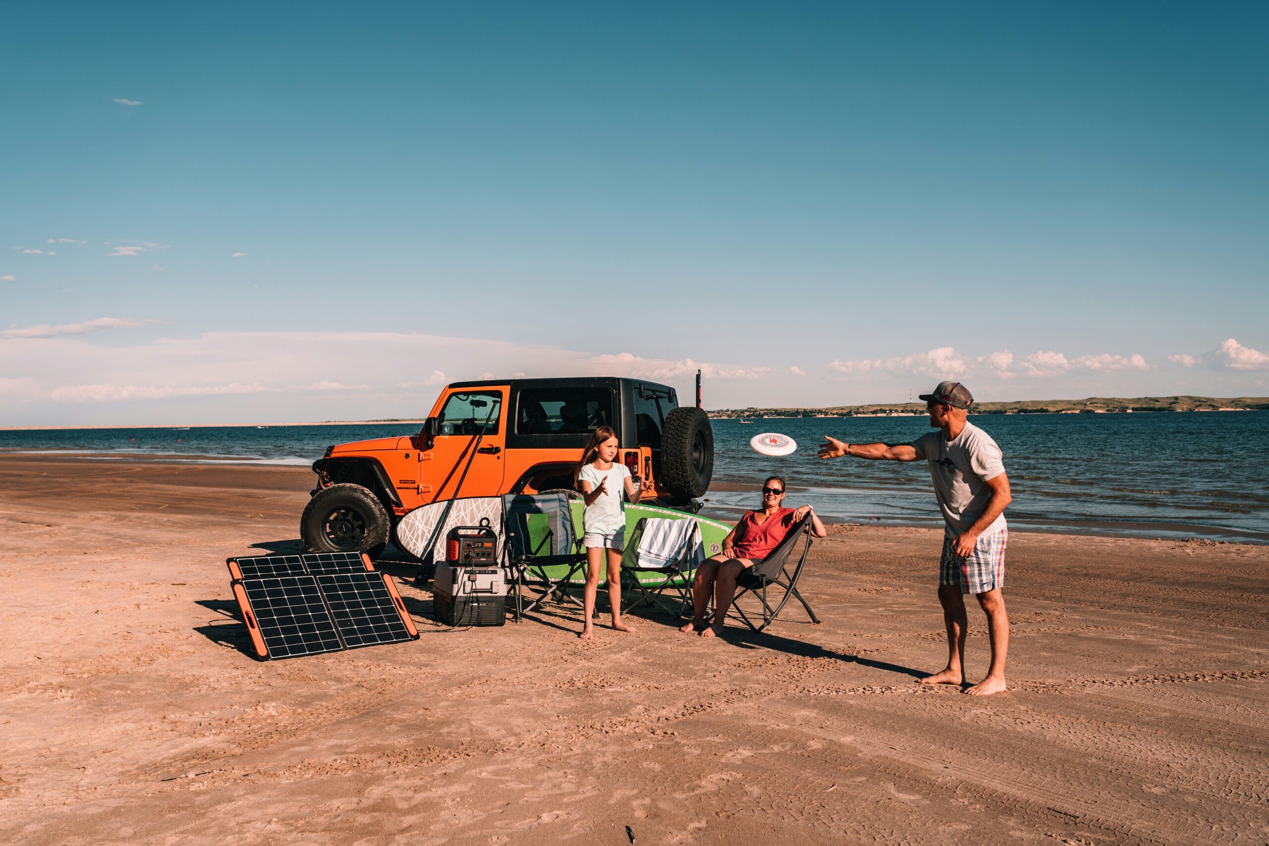 Family enjoying a beach day powered by their portable power station hooked to a solar panel