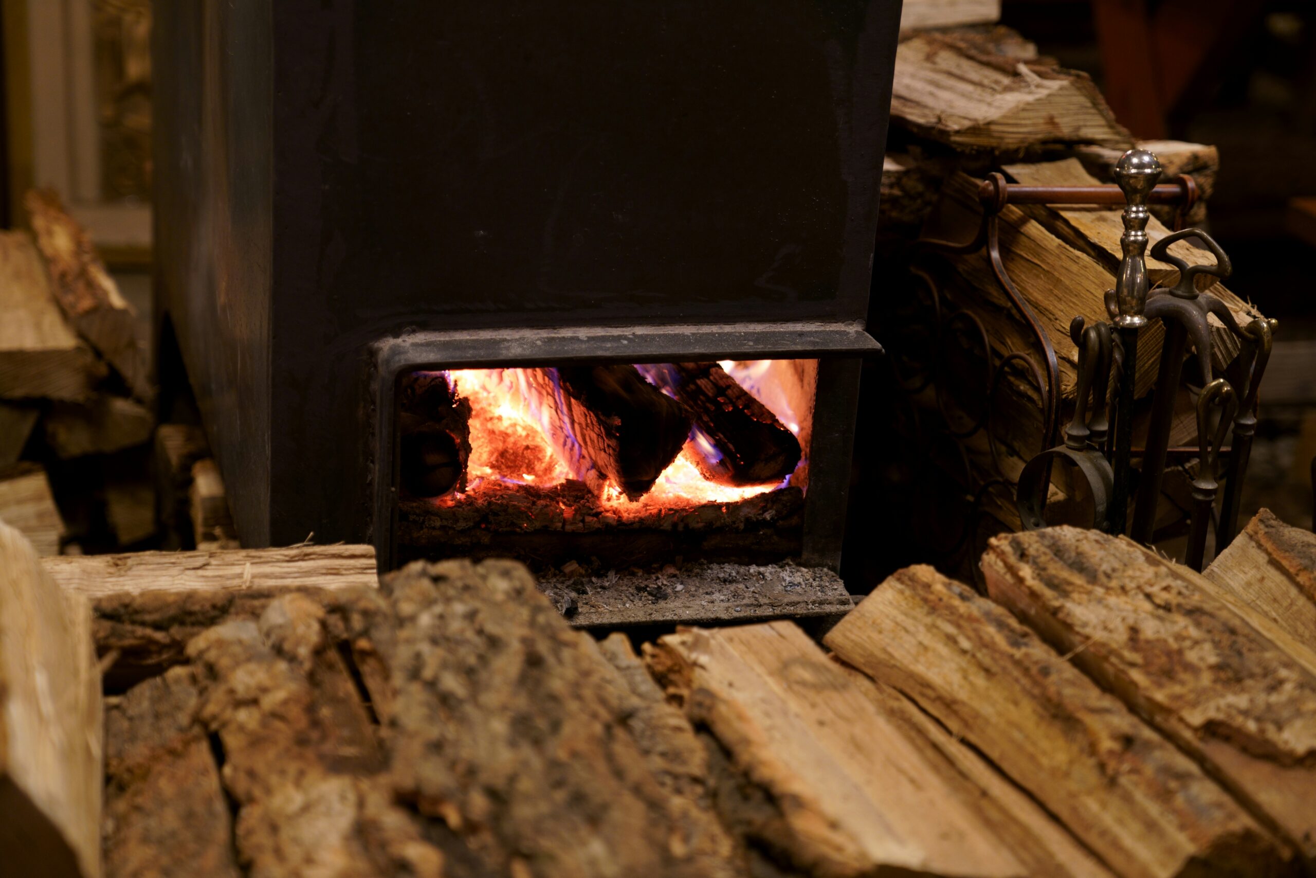 Wood burning stove in small cabin with a stock pile of wood in the forefront