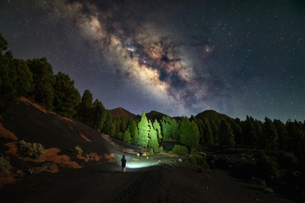 Person hiking under the stars using a bright powerful flashlight